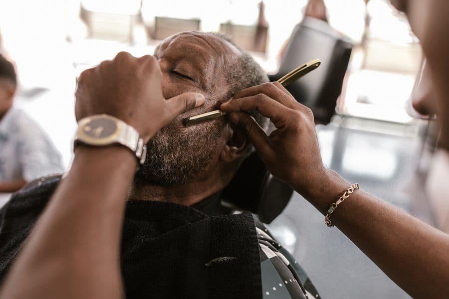 Barber shaping a client's beard with a razor