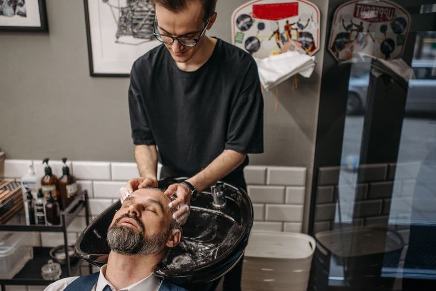 Barber washing a client's hair at the sink