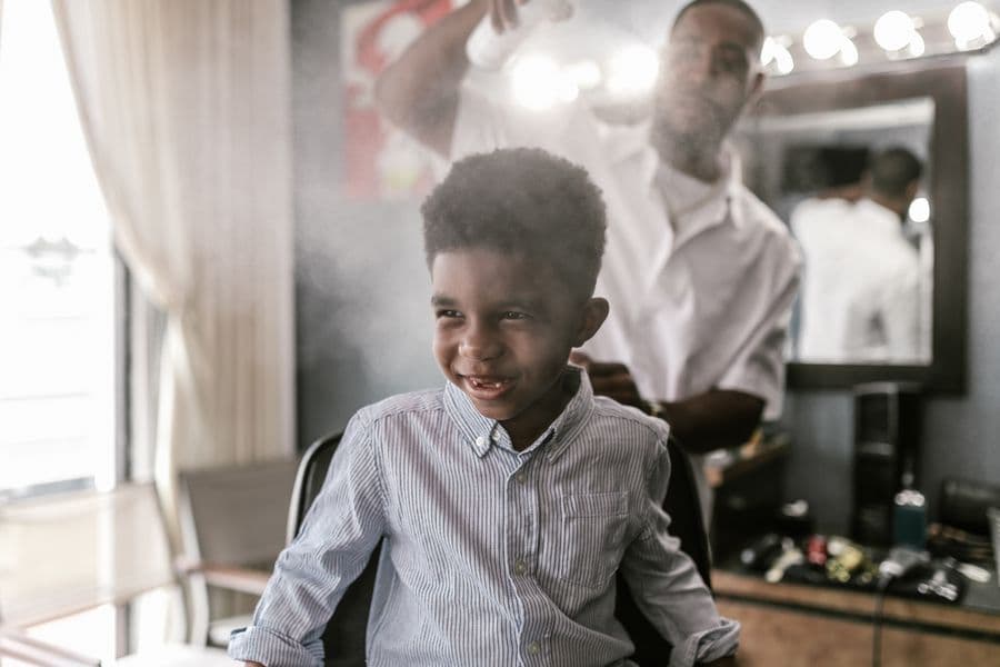 Young boy getting his first haircut in the chair