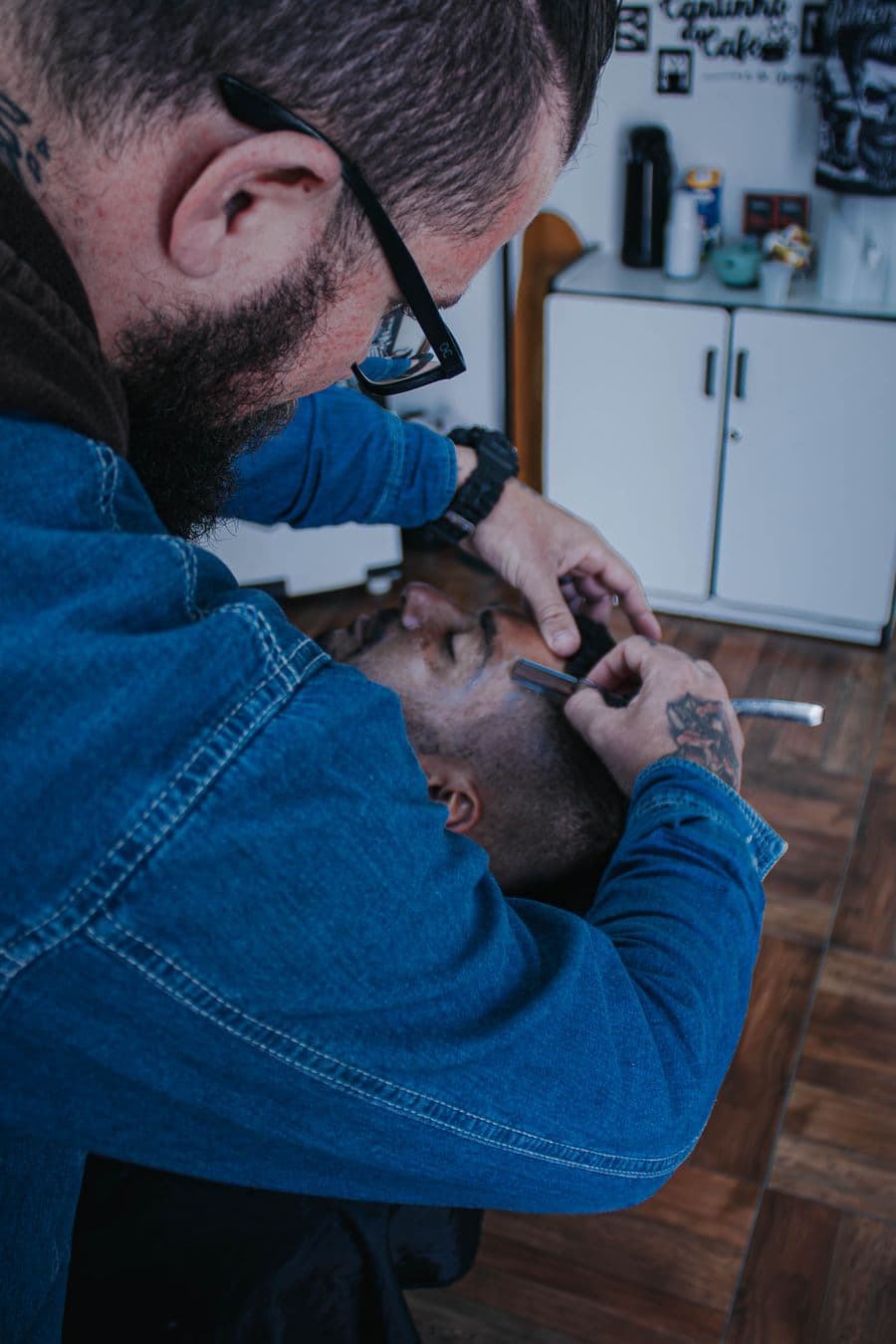 Barber tidying a hairline with an open razor